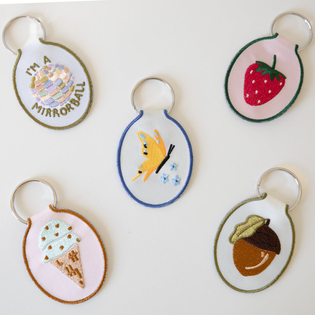 Embroidered keychains with 5 different designs displayed on a white background.