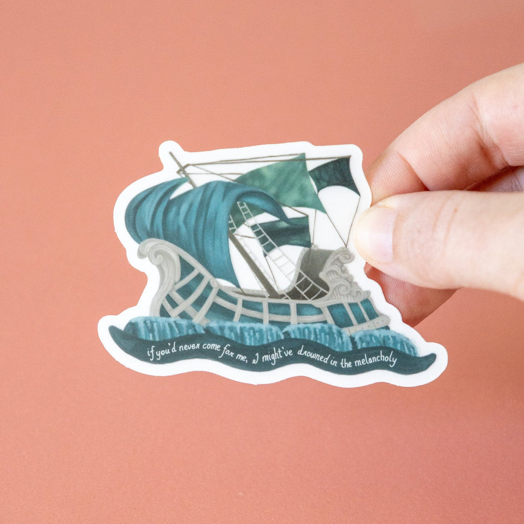Sticker of a ship in a wave held by a hand against a pink background