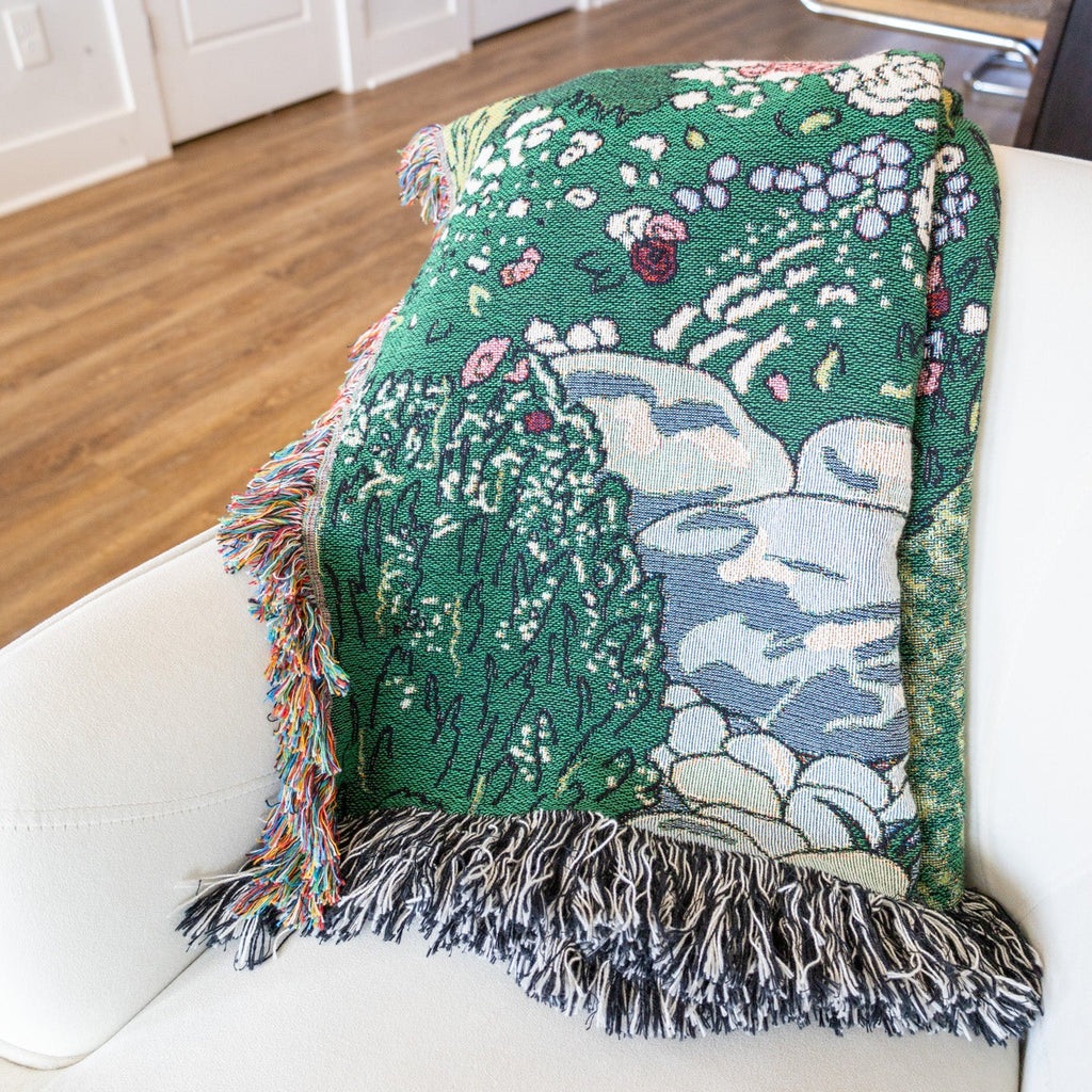 Decorative throw blanket with nature-themed design on a white chair.