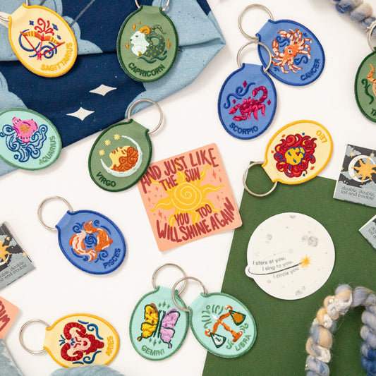 Collection of colorful keychains and gift items with various designs on a green surface