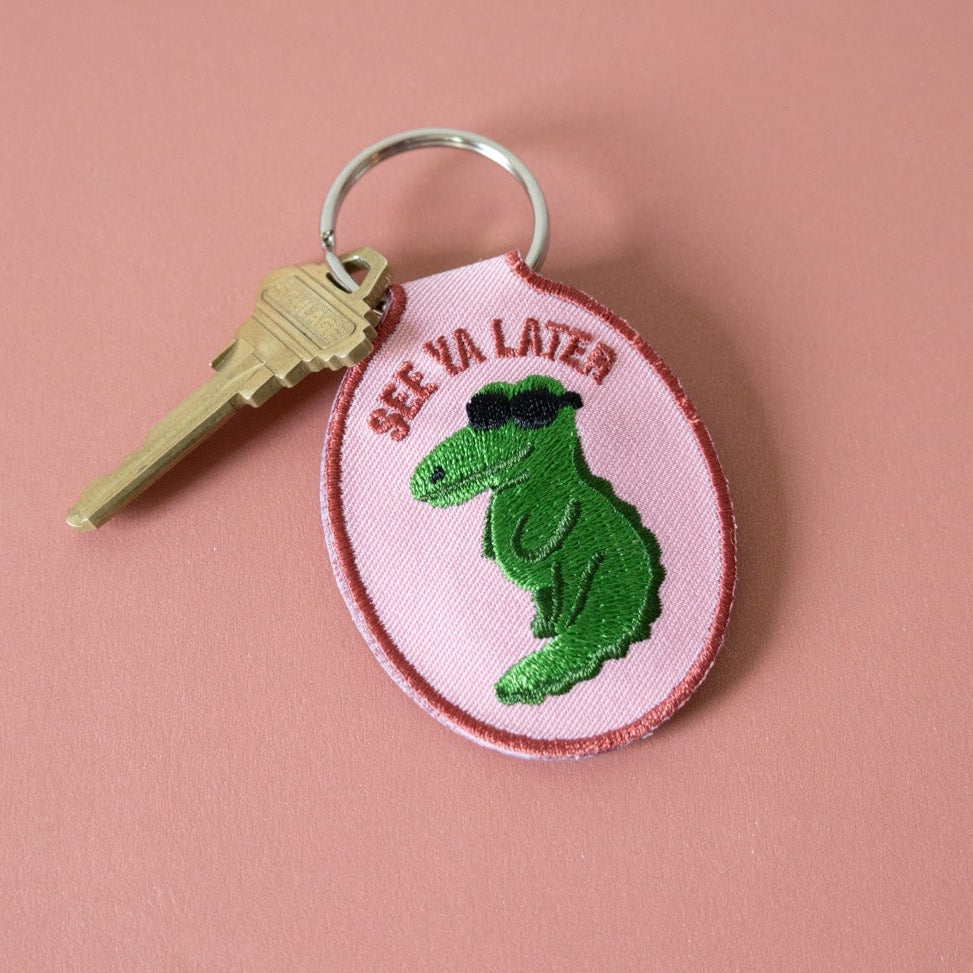 Keychain with green alligator design and 'See Ya Later' text on a pink background