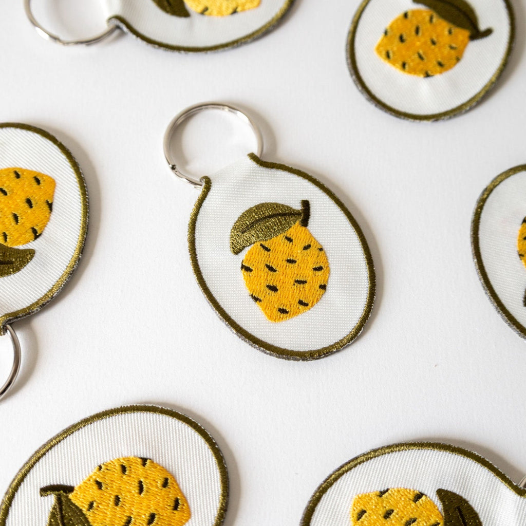 Embroidered lemon keychains against a white background.