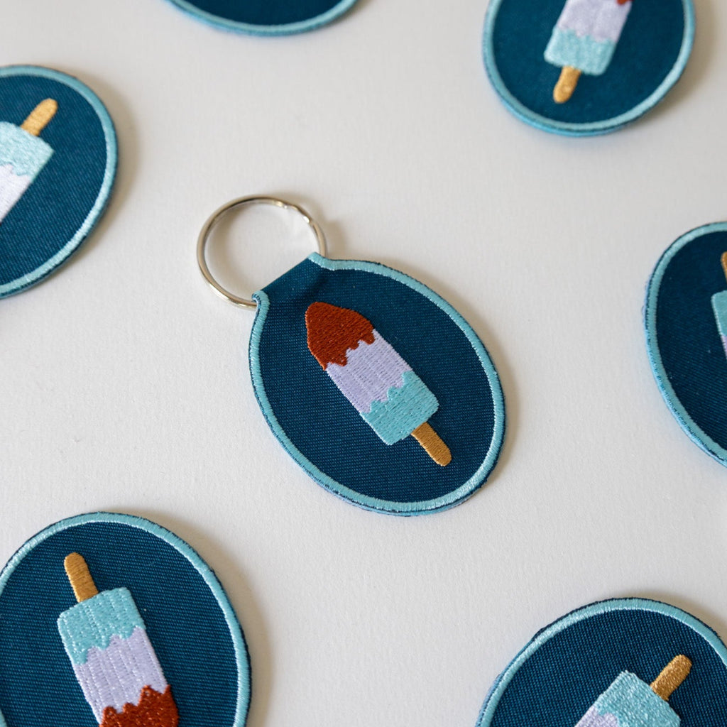 Embroidered keychains with red, white, and blue popsicle designs on a white background